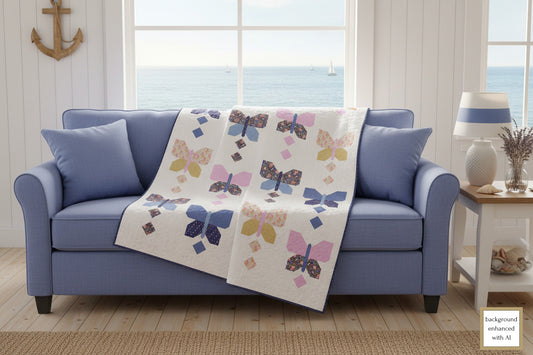 Blue sofa draped with a pastel butterfly pattern lap quilt designed by Coach House Designs. The large Pastel Butterflies are on a white background.