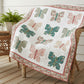 Lap quilt with butterfly patterns in floral pinks and greens on a white background with a decorative floral border