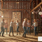 Group of people dancing in a rustic barn with wooden walls and decorative lights. Boots & Stripes quilt hanging on the wall of the barn.