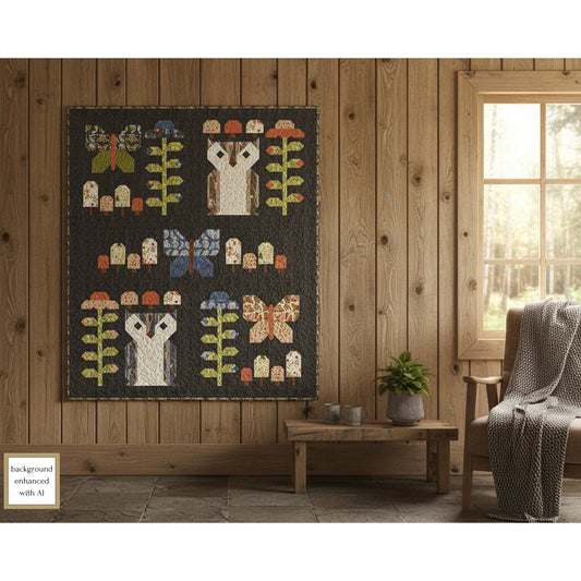 Lap quilt with owl blocks,  butterfly blocks, mushroom blocks and flower blocks hanging on a  wooden wall in a room with a window and chair.