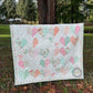 Kind Hearts lap quilt with large heart shaped heart pattern on a cream background draped over a country fence.