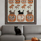 Framed quilt with Halloween-themed design on a wall above a gray sofa with a black cat.